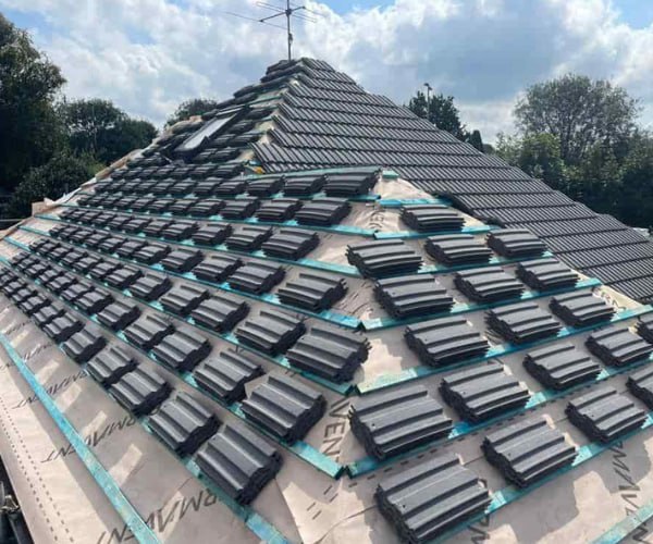 This is a photo of a new hip roof being installed. New felt, battens, and grey tiles have been installed, also a new velux window. Works carried out by EDS Roofing Stainforth