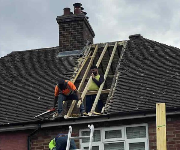 This is a photo of a roof repair being carried out. A section of the roof has been stripped and two roofers are replacing the rafters. Works being carried out by EDS Roofing Stainforth